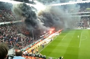 Dense, thick smoke raises from Cologne Stadium after fans ignite fire (Capture: Youtube) 